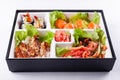 Fresh food portion in japanese bento box with salad, main course. Sushi roll with vegetables. Vegetarian dish.