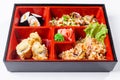 Fresh food portion in japanese bento box with salad, main course. Sushi roll with vegetables. Vegetarian dish.
