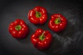 Fresh four red peppers on a black background in the center of the frame Royalty Free Stock Photo