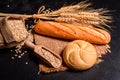 Fresh fragrant bread with grains and cones of wheat against a dark background Royalty Free Stock Photo