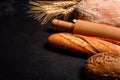 Fresh fragrant bread with grains and cones of wheat against a dark background Royalty Free Stock Photo