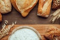 Fresh fragrant bread on the wooden table with cutting board and flour. Food concept