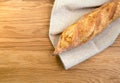 Crispy french baguette bread on a linen towel. Wooden background, fried crust . Top view. Bakery concept