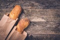 Fresh french baguettes in paper bags on wooden background, copy space. Bread shop