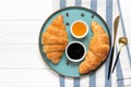 Fresh french croissants with chocolate on blue plate, blueberry jam, spoon, honey, napkin coffee grains on white background Royalty Free Stock Photo