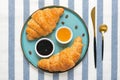 Fresh french croissants with chocolate on plate, blueberry jam, honey, napkin, coffee grains on gray granite background Royalty Free Stock Photo
