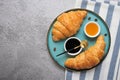 Fresh french croissants with chocolate on plate, blueberry jam, honey, napkin, coffee grains on gray granite background Royalty Free Stock Photo