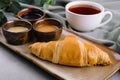 Fresh french croissants with chocolate on plate, blueberry jam, honey, and tea