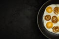 fresh fried eggs with onion rings in a frying pan on a black textured plaster background. top view. artistic dark moody photo with Royalty Free Stock Photo