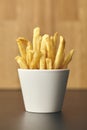 Fresh fried French Fries in white mug on wooden table. Close up