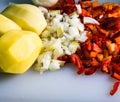 Fresh and frozen chopped vegetables,  Chopped carrots, potatoes, onions and red bell pepper on white cutting board Royalty Free Stock Photo
