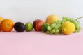 Fresh fruit apple, lime, avocado, lemon, orange, grapes on a light pink background Royalty Free Stock Photo