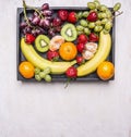 Fresh fruit, bananas, grapes, kiwi and tangerines, strawberries have been laid out in vintage wooden crate, top view, space for Royalty Free Stock Photo