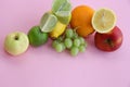 Fresh fruit apple, lime, avocado, lemon, orange, grapes on a light pink background Royalty Free Stock Photo