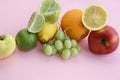 Fresh fruit apple, lime, avocado, lemon, orange, grapes on a light pink background Royalty Free Stock Photo