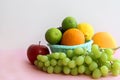 Fresh fruit in the basket apple, lime, avocado, lemon, orange, grapes on a light pink background Royalty Free Stock Photo