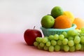 Fresh fruit in the basket apple, lime, avocado, lemon, orange, grapes on a light pink background Royalty Free Stock Photo