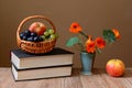 Fresh fruit in the of basket wicker, books and flowers Royalty Free Stock Photo