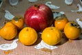 Kitchen still-life. Wholesome ripe fruits of pomegranate, mandarine and persimmon on a cute tablecloth. Royalty Free Stock Photo