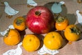 Kitchen still-life. Wholesome ripe fruits of pomegranate, mandarine and persimmon on a cute tablecloth. Royalty Free Stock Photo