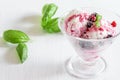 Fresh fruit ice cream in the glass bowl on the white table, green leaves of basil . Sweet dessert eating Royalty Free Stock Photo