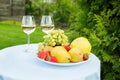 Fresh fruit on a plate and wineglass with white wine on a table in the garden