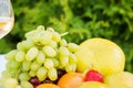 Fresh fruit on a plate and wineglass with white wine on a table in the garden Royalty Free Stock Photo