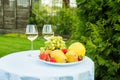 Fresh fruit on a plate and wineglass with white wine on a table in the garden Royalty Free Stock Photo