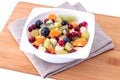 Vitamin fruit salad from slices of kiwi, tangerine, apples, grapes for morning breakfast in a white bowl. Royalty Free Stock Photo