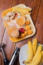 Fresh fruit smoothie with banana and apricots at orange  tray  with blender  at wooden table. flat lay Royalty Free Stock Photo
