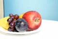 Fresh fruit on a white plate against a blue wall, healthy food concept Royalty Free Stock Photo