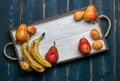 Fresh fruit on a white wooden tray: banatas, pears, apricots. Countryside setting. Top view.