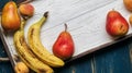 Fresh fruit on a white wooden tray: banatas, pears, apricots. Countryside setting. Top view. Royalty Free Stock Photo