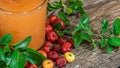 Fresh fruits and acerola juice (Malpighia emarginata) between leaves on wooden background