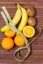 Fresh fruits banana, kiwi, orange wrapped in a centimeter, isolated on wooden background. Healthy food. Fitness motivation. Royalty Free Stock Photo