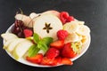Fresh fruits and berries on plate apples, strawberries, bananas, cherries, peaches