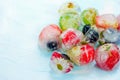 Fresh fruits and berry frozen in ice cubes on blue background. F
