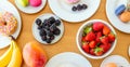 Colorful breakfast top view. Fresh fruits, donuts and macarons on wood. Banana, strawberry, blackberry and mango Royalty Free Stock Photo