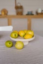 Fresh fruits lemons and green apples are on a white plate on the kitchen table Royalty Free Stock Photo