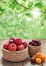Fresh fruits on old wooden table over bokeh garden background, apples and cherries in baskets Royalty Free Stock Photo