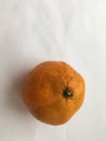 One ripe orange mandarin lying on a white background. Abstract wallpaper.