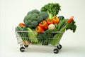 Fresh fruits and vegetables in stocked supermarket cart, isolated on white background