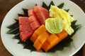 Fresh fruits on white plate with natural banana leaf arrangement. Cut Healthy fruits, papaya, watermelon, pineapple on a plate. Royalty Free Stock Photo