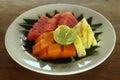 Fresh fruits on white plate with natural banana leaf arrangement. Cut Healthy fruits, papaya, watermelon, pineapple on a plate. Royalty Free Stock Photo