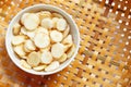 Fresh galangal slices in white bowl on wooden bamboo threshing basket background Royalty Free Stock Photo