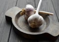 Fresh garlic bulbs in wooden plate over old dark wooden board Royalty Free Stock Photo