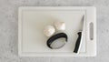 Fresh garlic, kitchen knife, and garlic press close-up on a white cutting board, flat lay Royalty Free Stock Photo
