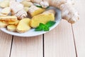 Fresh ginger root sliced and mint leaves on a white plate and a light wooden background. Royalty Free Stock Photo