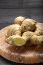 Fresh ginger roots on pink salt board close up on black wooden background