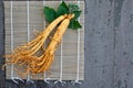 Fresh ginseng root on bamboo basket with green leaves and berries Royalty Free Stock Photo